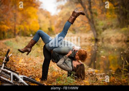 Romantico coppia giovane ingannare circa su riverside in autunno Foto Stock