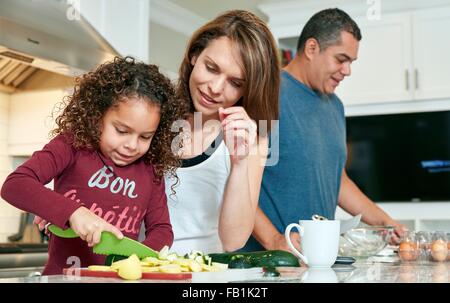 Madre aiutare mia figlia tritare verdure in cucina Foto Stock