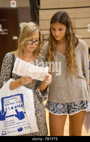 In un college fair di Aliso Viejo, CA, a madre e figlia di leggere un elenco di domande da porre al collegio rappresentanti circa che cosa rende le loro istituzioni desiderabile per un richiedente. Nota il sacchetto in plastica azienda brochure. Foto Stock