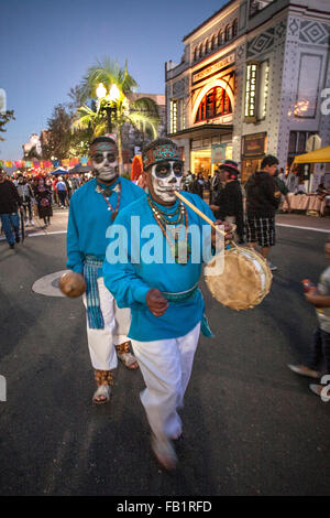 Indossando il trucco che assomiglia alla faccia di La Calavera Catrina ('Dapper scheletro'), artisti di strada che porta i tamburi e flauti a piedi la strada durante il giorno dei morti o Dia de Muertos vacanza tra gli ispanici in Santa Ana CA. La vacanza si concentra su gathe Foto Stock