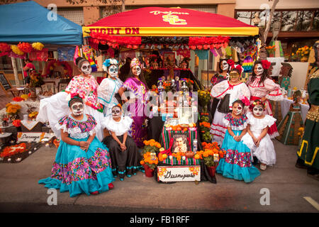 Indossando il trucco che assomiglia alla faccia di La Calavera Catrina ('Dapper scheletro') i familiari pongono a un altare in onore di un parente deceduto durante il giorno dei morti o Dia de Muertos vacanza tra gli ispanici in Santa Ana CA. La vacanza si concentra su gathe Foto Stock