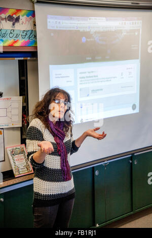 Un San Clemente, CA, quarto grado insegnante risponde a uno studente che domanda. Nota proiettata immagine del computer sullo schermo. Foto Stock