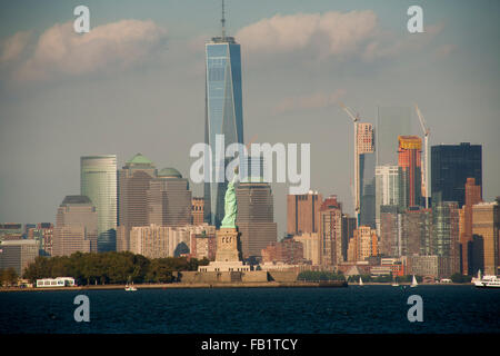 La Statua della Libertà su Liberty Island nel porto di New York è giustapposto con One World Trade Center come visto da Jersey City, NJ. Foto Stock