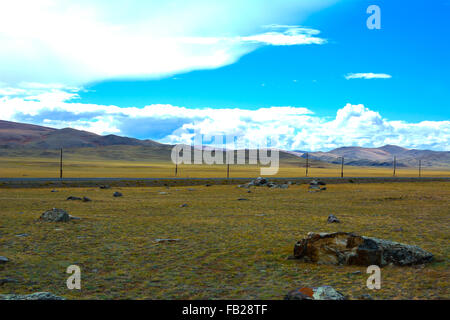 Steppa luminoso paesaggio con una strada e grosso pezzo di roccia in primo piano, vista montagne, cielo blu con nuvole. Chuya steppa, Foto Stock