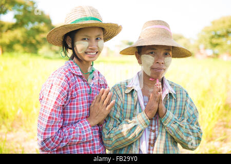 Ritratto di due Myanmar agricoltori femmina con thanaka faccia in polvere che mostra il gesto di saluto alla risaia. Foto Stock