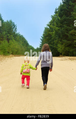 Piccole sorelle andare su una strada forestale tenendo le mani Foto Stock