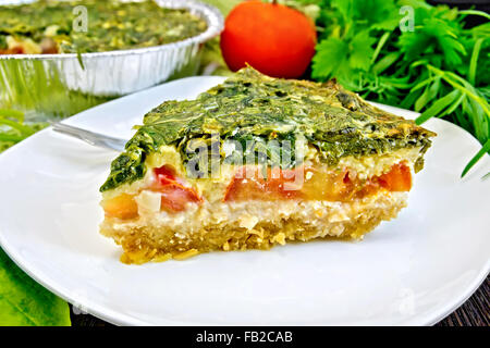 Celtic torta con spinaci, pomodori, fiocchi d'avena e le uova in una piastra bianca a forma di lamina di cottura, prezzemolo su tavole di legno bac Foto Stock