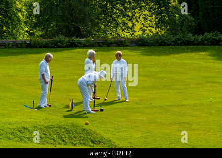 Gruppo di persone anziane donne caucasici giocando croquet su un prato verde in un sole estivo Foto Stock