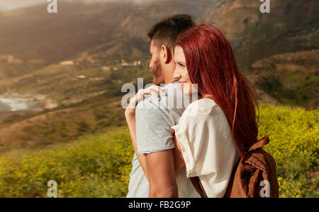 Romantico coppia giovane per visitare i siti turistici durante le escursioni attraverso la montagna. Giovane donna che abbraccia il suo ragazzo da dietro, WH Foto Stock