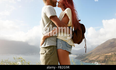 Ritagliato colpo di giovane uomo e donna in piedi vicino a ciascun altra faccia a faccia. Coppia romantica abbracciando all'esterno. Foto Stock