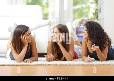 Gruppo di felice teen amici parlando sdraiato sul pavimento a casa Foto Stock