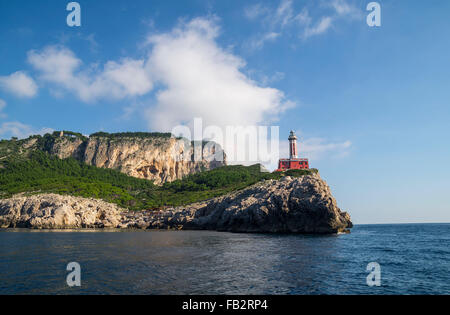 Faro di Punta Carena sulle rocce costiere al Mar Mediterraneo in Isola di Capri, visto da una barca a motore tour. Foto Stock