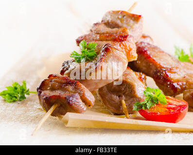 Spiedini di carne di maiale servito con le verdure su un tavolo di legno. Messa a fuoco selettiva Foto Stock