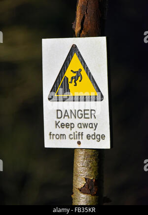 'Drabbia tenere lontano dal bordo scogliera". Segnale di avvertimento per l'albero. Cascate del Clyde, Bonnington, South Lanarkshire, Scozia, Regno Unito, Europa. Foto Stock