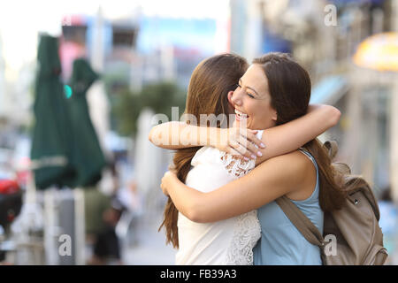 Felice incontro di due amici abbracciando in strada Foto Stock