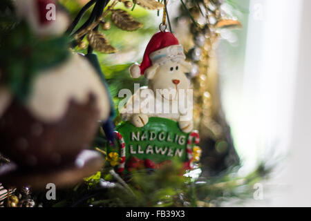 Decorazione di natale di una pecora tenendo un cartello che diceva "Nadolig Llawen' che è un messaggio di saluto di Natale in gallese. Foto Stock