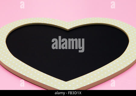 Amore forma di cuore blackboard su uno sfondo rosa Foto Stock