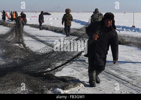 (160109) -- SONGYUAN, gen. 9, 2016 (Xinhua) -- i pescatori cercano di tirare una rete da pesca al di fuori dell'acqua sul lago Chagan in città Songyuan, a nord-est della Cina di provincia di Jilin, 8 gennaio, 2016. Lago Chagan, che è noto per le tradizionali attività di pesca invernale che risale ai tempi preistorici, è l'unico posto che salva il mongolo più antico metodo di pesca. Durante l'inverno annuale Pesca Festival che si tiene a ricordare il vecchio inverno tradizione della pesca, i pescatori prima praticare molti fori attraverso l'uno spesso strato di ghiaccio e poi posto un netto sotto il ghiaccio. La rete potrà finalmente tirato fuori da un cavallo-verricello di disegno. Th Foto Stock