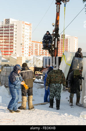 UFA - RUSSIA 19dicembre 2015 - russo della scultura di ghiaccio lavoratori pianificare e installare il blocco di ghiaccio per creare divertimento invernale in Foto Stock