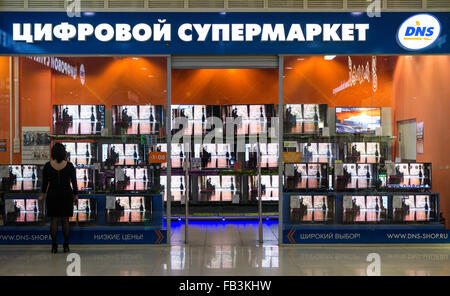 UFA - RUSSIA 19dicembre 2015 - unica ragazza in un abito nero guarda in una televisione russa store chiamato DNS in Ufa, Russia Foto Stock