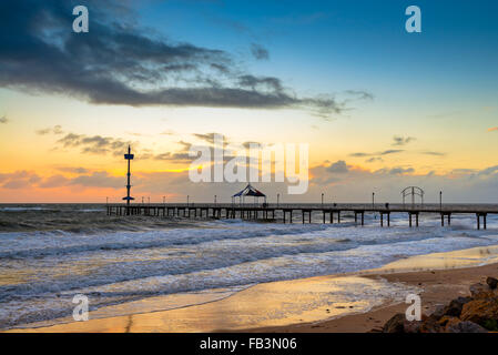 Surfer sul molo di Brighton al tramonto sul maltempo in Sud Australia Foto Stock