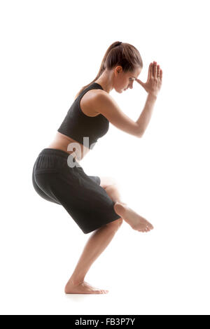 Yoga sportivo girl su sfondo bianco in piedi su una gamba sola con palme piegato in mudra Foto Stock