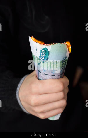 Persona afferra pack di bruciatura delle banconote in russo con valore nominale di mille macerie Foto Stock