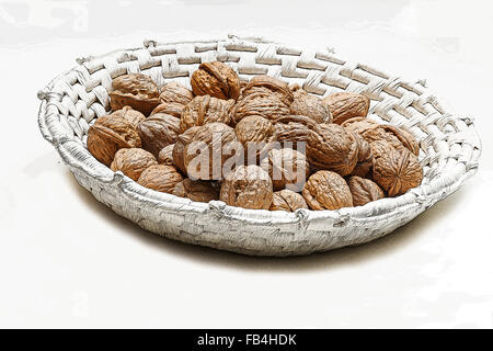 Le noci in un cesto bianco su sfondo bianco Foto Stock