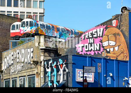 Il tubo di riciclo carrozze ferroviarie utilizzate come artisti studios arroccato sopra il vecchio viadotto ferroviario con pareti utilizzato per arty graffiti Foto Stock