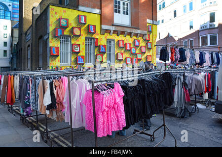 Vestiti scelte per lo shopping da rotaie visualizzazione su capi di abbigliamento in vendita in Petticoat Lane market Londra Inghilterra REGNO UNITO Foto Stock