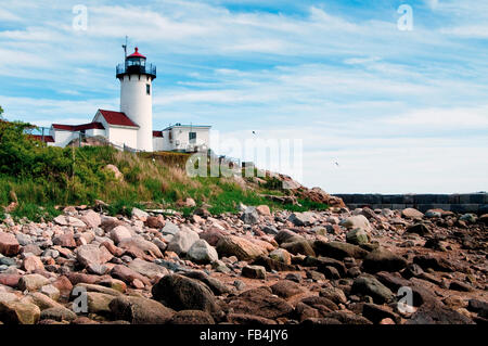 La bassa marea visualizza costa rocciosa intorno al punto orientale faro in Gloucester, Massachusetts. Il radiofaro protegge i naviganti entrando in porto di Gloucester. Foto Stock