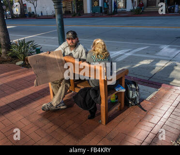 Un senzatetto coppia sposata mendica mentre è seduto su una panchina su State Street a Santa Barbara, California. Foto Stock