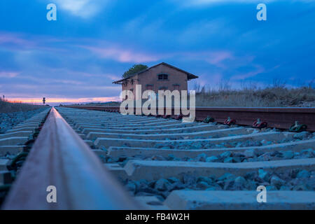 I binari ferroviari con abbandonata la stazione rurale al crepuscolo, Badajoz, Spagna Foto Stock