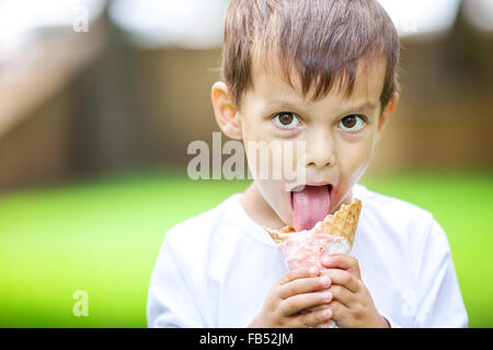 Giovane ragazzo a mangiare il gelato all'aperto Foto Stock