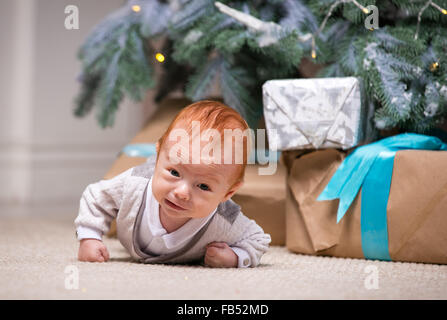 Carino baby boy sotto albero di Natale a casa Foto Stock