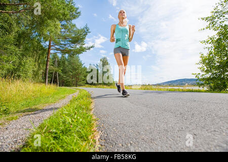 Sorridente giovane donna treni su una strada nella foresta Foto Stock