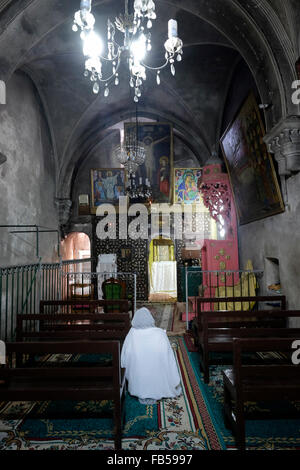 Il cristiano ortodosso etiope prega all'interno della sezione superiore della "Cappella Dei Quattro Animali" della chiesa etiope sotto il monastero di Deir El-Sultan, che si trova sul tetto della Chiesa del Santo Sepolcro nella città vecchia di Gerusalemme Est Israele Foto Stock