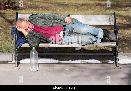 Sofia, Bulgaria - 8 Gennaio 2016: un senzatetto è dormire su una panchina in un parco nella capitale bulgara. Anni dopo unire Foto Stock