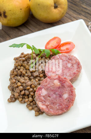 Piatto di lato di sausagecotechino e le lenticchie con il prezzemolo e il pomodoro sweet Foto Stock