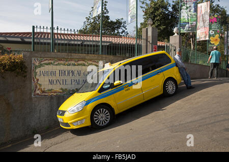 Yellow taxi parcheggiato su una ripida collina al di fuori dei giardini tropicali in Monte di Madera Foto Stock