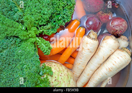 Verdure sporco in un lavello riempito con acqua. Foto Stock