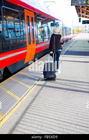 Travling donna a un treno all'aperto il terminale Foto Stock