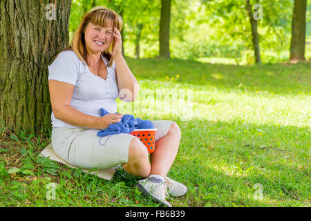 Ritratto di ridere 50 anno vecchia donna nel parco dedicato a maglia Foto Stock