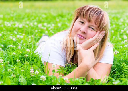Felice coppia donna sdraiata su un prato e sorridente Foto Stock
