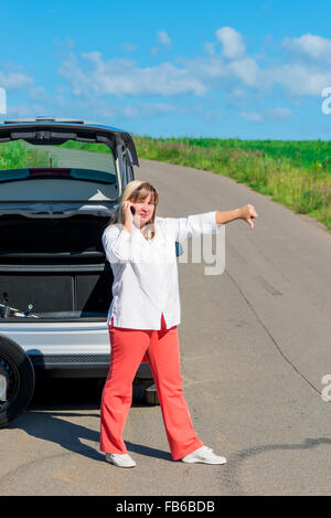 Addolorato donna vicino alla vettura rotto con il telefono Foto Stock