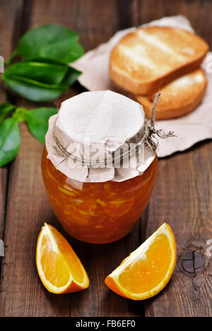 Orange marmellata, fette di pane e sul tavolo di legno Foto Stock