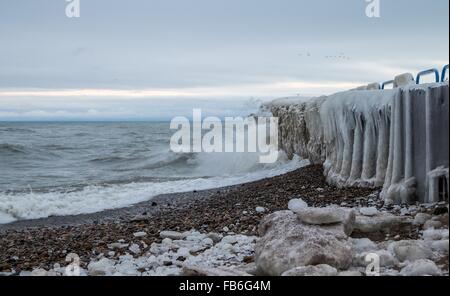 Inverno Seashore paesaggio. Coperte di ghiaccio pier con onde che si infrangono sulla spiaggia sulla costa del Lago Huron. Port Sanilac, Michigan. Foto Stock