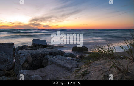 Tramonto sulla spiaggia orizzonte. Il tramonto sulla costa rocciosa di un lago Michigan beach. Ludington parco dello stato. Ludington, Michigan. Foto Stock