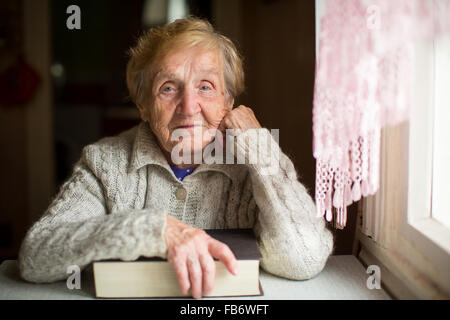 Una vecchia donna si siede con un libro. Foto Stock