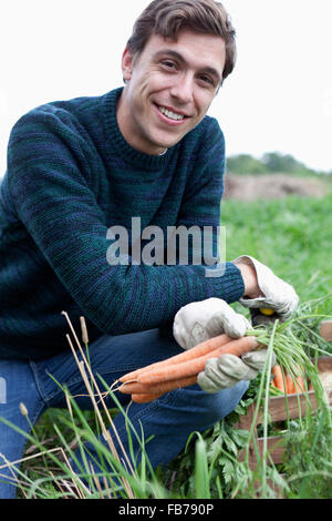 L'uomo la raccolta di carota nel campo, ritratto Foto Stock